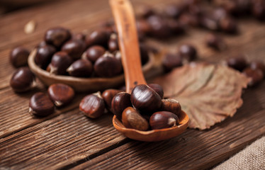 Chestnuts in a spoon on a wooden table.