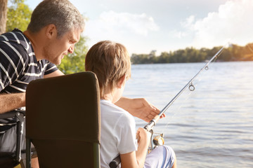 Fototapeta premium Father with son fishing from riverside