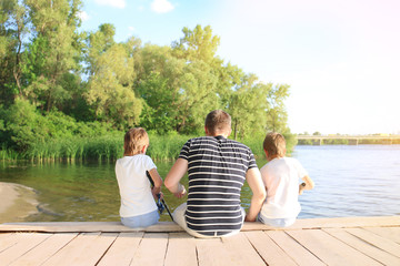 Fototapeta premium Father with sons fishing from pier on river