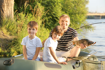 Father with sons fishing from boat on river