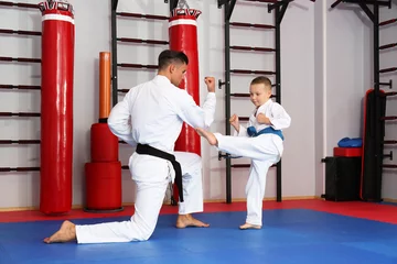 Keuken foto achterwand Vechtsport Mannelijke karate-instructeur die klein kind opleidt in dojo