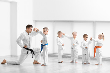 Kleine Kinder mit Lehrer üben Karate im Dojo