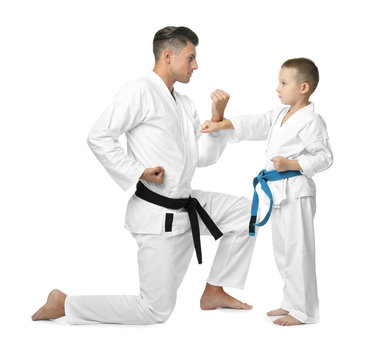 Little child with instructor practicing karate on white background