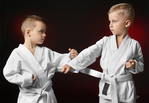 Little children practicing karate on dark background