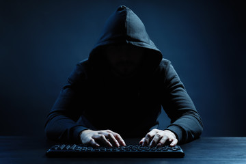 Hacker using keyboard on dark background