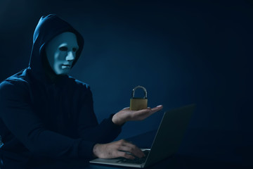 Hacker with lock using laptop on dark background