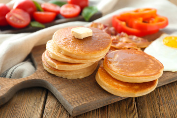 Board with yummy pancakes on wooden table