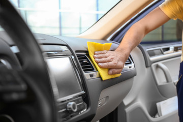 Man cleaning car dashboard with rag, closeup