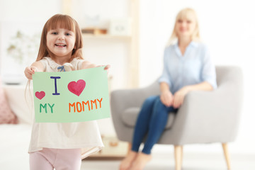 Little girl holding greeting card for Mother's day at home