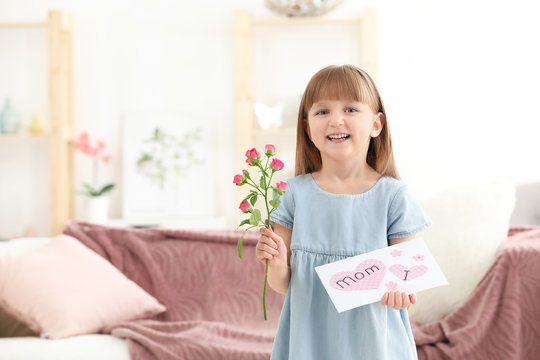 Little girl holding greeting card and flower for Mother's day at home