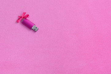 Brilliant pink usb flash memory card with a pink bow lies on a blanket of soft and furry light pink...