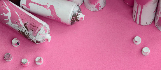 Some used pink aerosol spray cans and nozzles with paint drips lies on a blanket of soft and furry...