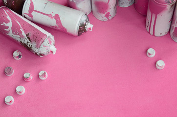 Some used pink aerosol spray cans and nozzles with paint drips lies on a blanket of soft and furry...