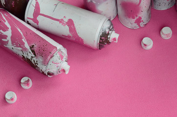 Some used pink aerosol spray cans and nozzles with paint drips lies on a blanket of soft and furry...