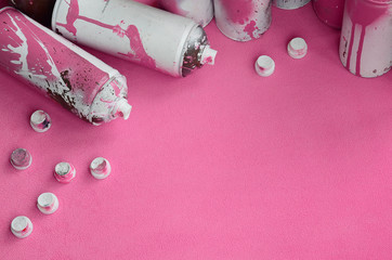 Some used pink aerosol spray cans and nozzles with paint drips lies on a blanket of soft and furry...