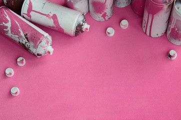 Some used pink aerosol spray cans and nozzles with paint drips lies on a blanket of soft and furry...