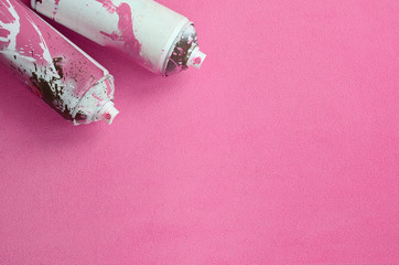 Some used pink aerosol spray cans with paint drips lies on a blanket of soft and furry light pink...