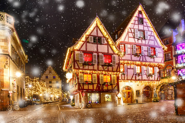 Traditional Alsatian half-timbered houses in old town of Colmar, decorated and illuminated at snowy christmas night, Alsace, France - obrazy, fototapety, plakaty