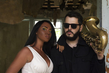 Young beautiful girl singer  with saxophone players on old house background. musical duet 