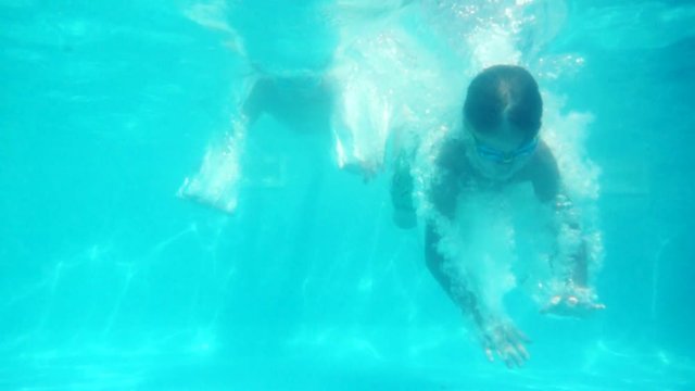 boys in goggles dives in blue pool in slow motion