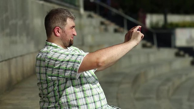 Fat man records video on smartphone. Guy makes photos on cell phone