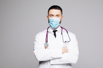 Portrait of a handsome beard doctor in scrubs with stethoscope and mask standing confidently on white background