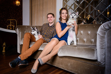 Beautiful young couple in the New Year atmosphere with puppies of the Husky