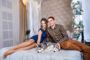 Beautiful young couple in the New Year atmosphere with puppies of the Husky - 183690843
