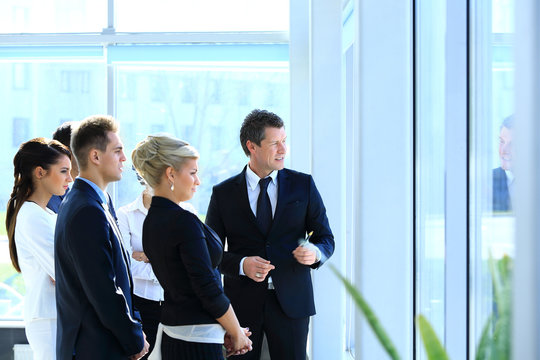 Group Of Business People Looking Out The Window,standing In The Lobby Of The Office.