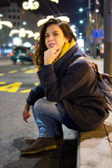 Urban girl sitting by the road at night