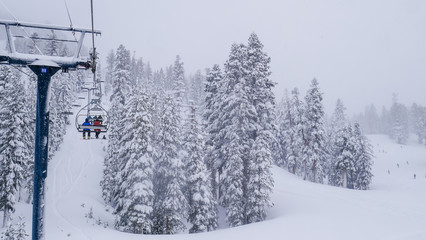 16x9, wide screen. Lift system at ski resort in California, Mammoth mountain. Fir trees covered by...