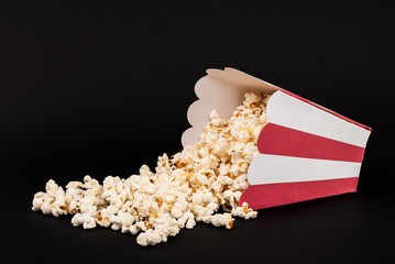 Popcorn spilled on black background © Emilija