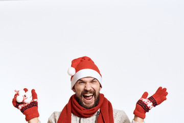 a man with a beard rejoices, Christmas decorations in his hand, gloves, a light background, free space for copying, a new year