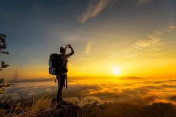 A backpacker girl travels on the mountains ahead as the sea fog and sunrise.