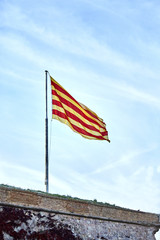 Flying flag of Catalonia against blue sky. Catalonia flag waving against clear blue sky