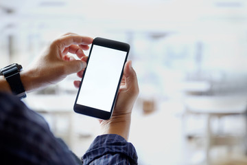 Mockup image of man hands holding black mobile phone with blank white screen in office.