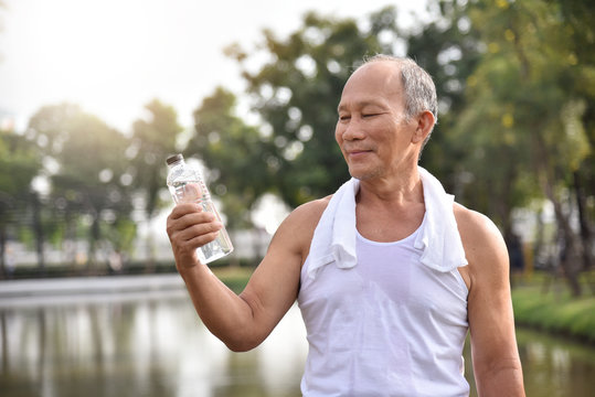 Asian senior male holding bottle of water.