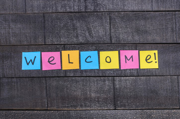 The word "welcome!" on colored stickers on a dark background