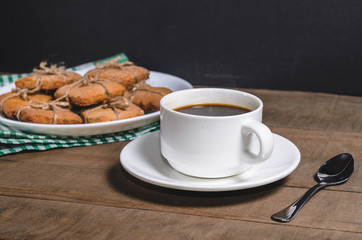 Black coffee in a white cup on a green napkin and homemade cookies.