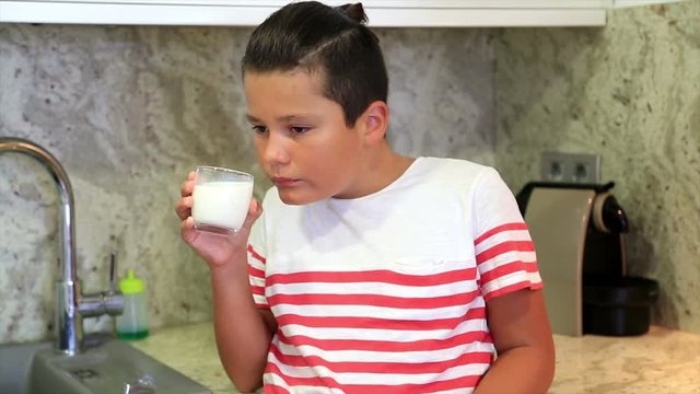 Portrait of a cute preteen boy drinking milk in the kitchen