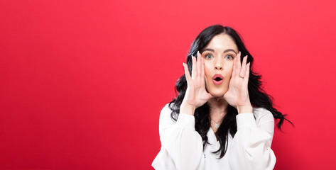 Young woman shouting an annoucment on a solid background