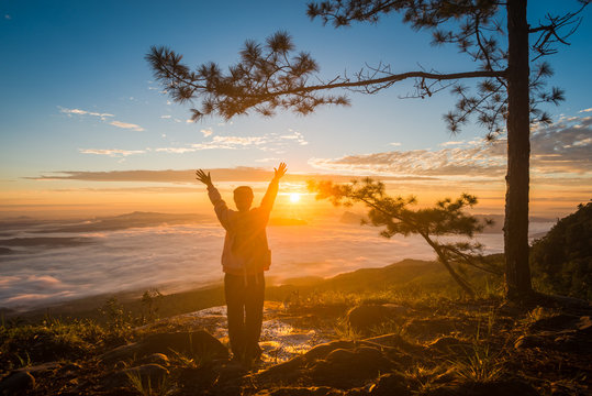 Young Woman Watching The Sun Rise From Top Of Mountain