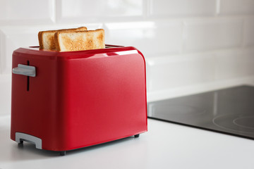 Red toaster with toasted bread for breakfast inside. White background. White kitchen table. - 183708211