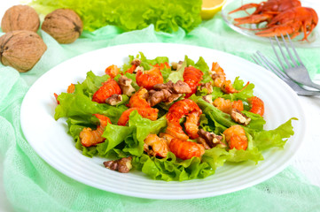 Light dietary spicy salad of lettuce, seafood (crawfish, shrimp) and walnuts on a white wooden background. Proper nutrition