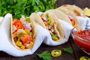 Mexican tacos with meat, corn, tomatoes, sweet pepper, red onions in a wheat tortilla with a spicy...