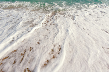 White foam and azure sea, sand and water foam, soft wave of blue ocean and sandy beach
