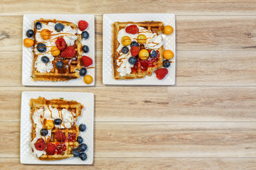belgian waffle with raspberries and blueberries on wood table.