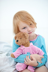 Red-haired girl hugs her teddy bear on the white background