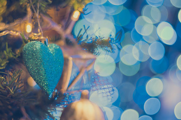 heart shape ornament on christmas tree decoration with blue light bokeh as background