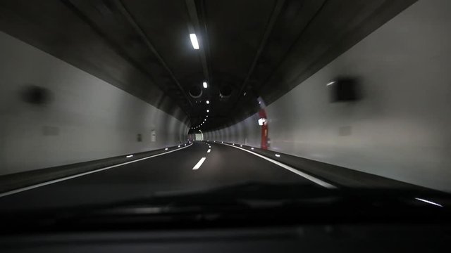 Car traveling on the A2 freeway on a rainy night in and out of tunnel in Leventina vallaey, Ticino 